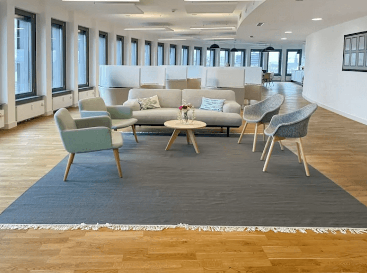Heller Wartebereich mit Sofa, Sesseln, Couchtisch und großem Teppich